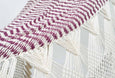 Close-up of mixed cotton weave and hand-tied fringe on deep red boho hammock