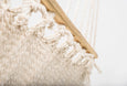 Handwoven hammock with fringe detailing, displayed on a shaded terrace