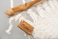 Detail view of natural cotton weave and fringe on a handmade hammock with teak wooden bar
