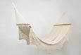Luxury boho hammock in natural cotton, shown suspended with a wooden bar