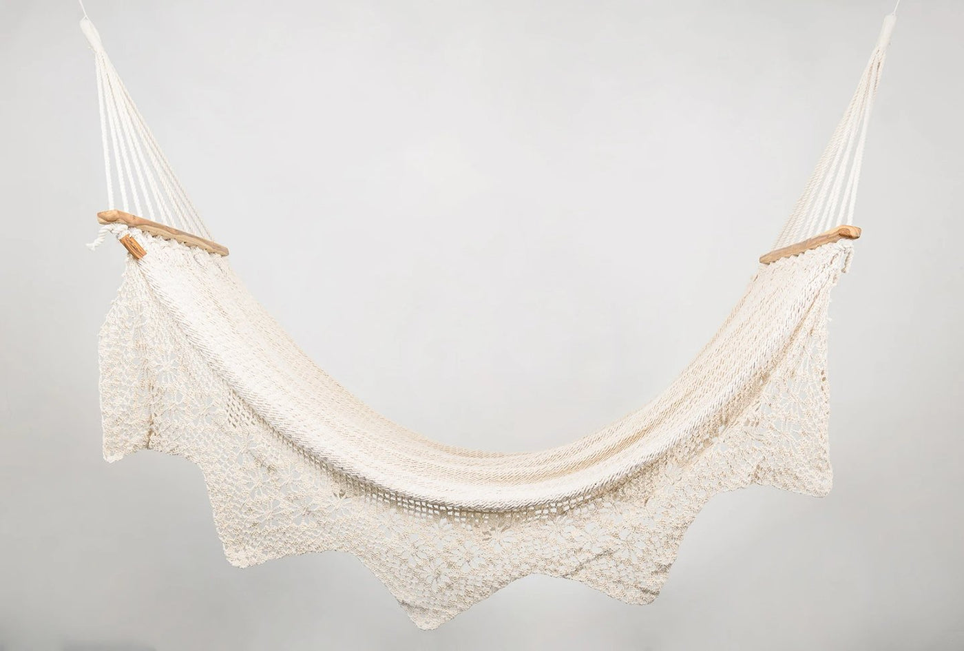 Handwoven natural cotton hammock in natural color with solid teak bar and geometric fringe