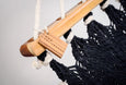 Close-up of artisan hand-tied tassels on black cotton hammock with rich teak spreader bar