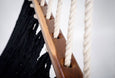 Close-up of artisan hand-tied tassels on black cotton hammock with rich teak spreader bar
