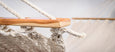 Close-up of artisan tassel details on neutral cotton hammock with solid teak spreader bar