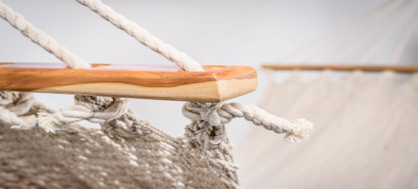 Close-up of artisan tassel details on neutral cotton hammock with solid teak spreader bar