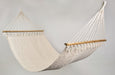Luxury cotton hammock with wooden bar, styled outdoors with soft shadows and boho decor.