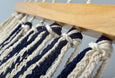 Close-up of hand-tied tassels on navy cotton hammock with rich teak bar craftsmanship