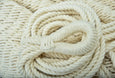 Close-up of an elegant indoor or outdoor hammock in deep navy cotton, featuring teak bar and sculptural macramé fringe